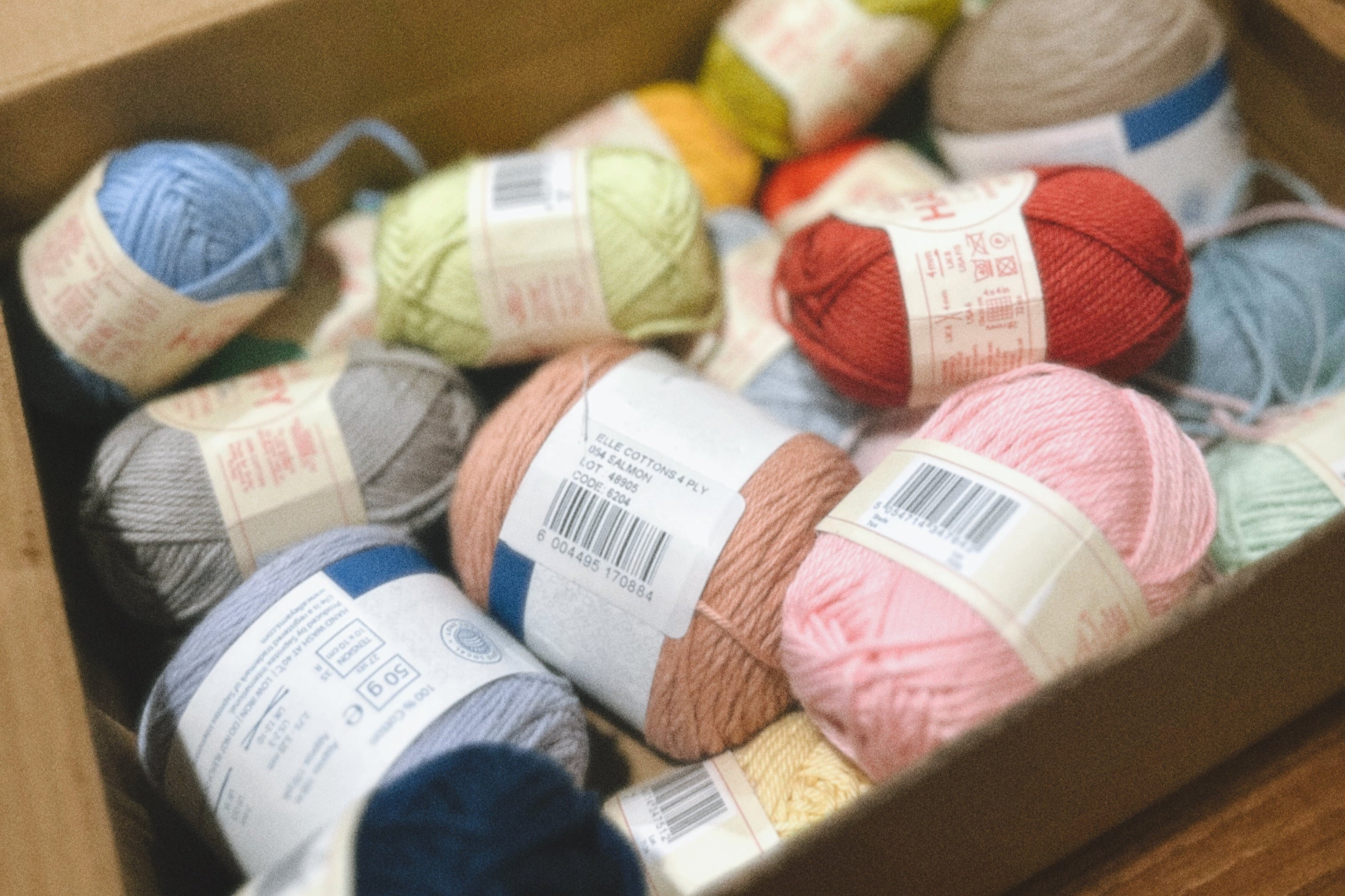 Box filled with colorful yarn balls on a wooden surface
